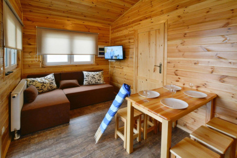 Gezellig houten interieur in Domki wakacyjne Przewłoka met zithoek, eettafel en tv aan de muur.