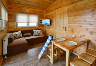 Gezellig houten interieur in Domki wakacyjne Przewłoka met zithoek, eettafel en tv aan de muur.