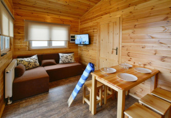 Acogedor interior de madera en Domki wakacyjne Przewłoka con sofá, mesa de comedor y televisor.