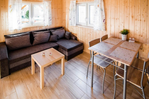 Lichte leefruimte van Ustecka Osada 45m2 met grijze zetel, eettafel en houten wanden, Denemarken.