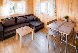 Lichte leefruimte van Ustecka Osada 45m2 met grijze zetel, eettafel en houten wanden, Denemarken.