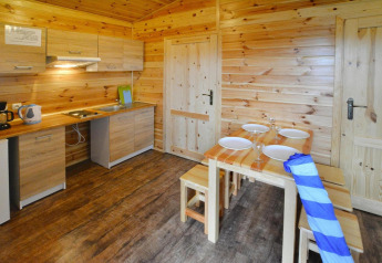 Gemütliche Holzküche mit Esstisch, Geschirr und modernen Geräten in Domki wakacyjne Przewłoka.