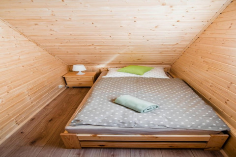 Knusse houten slaapkamer met dubbel bed, nachtkastje en lamp in Ustecka Osada 45m2 in Denemarken.