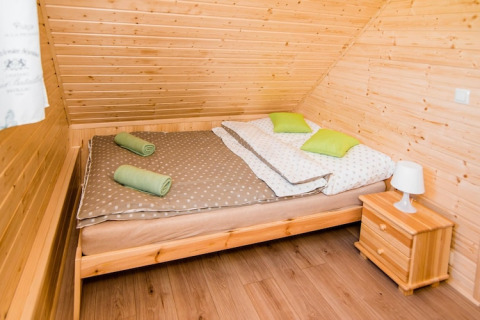 Knusse slaapkamer in lodge Ustecka Osada 45m2 in Denemarken met houtinrichting en tweepersoonsbed.