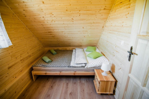 Slaapkamer in Ustecka Osada 45m2 lodge te Denemarken met houten bekleding, dubbel bed en nachtkastje.