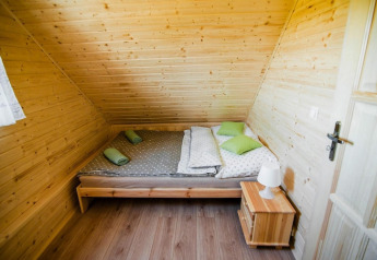 Gemütliches Schlafzimmer in der Ustecka Osada 45m2 Lodge in Dänemark mit Holzwänden und Doppelbett.