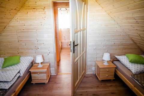 Gezellige slaapkamer in lodge «Ustecka Osada 45m2» in Denemarken met twee bedden en houten interieur.