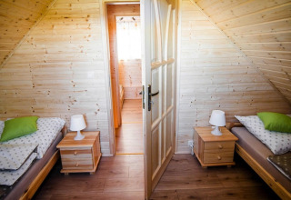 Gezellige slaapkamer in lodge «Ustecka Osada 45m2» in Denemarken met twee bedden en houten interieur.
