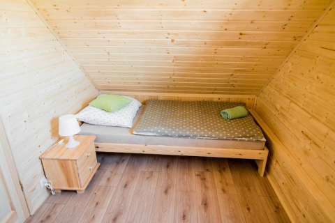 Gezellige slaapkamer in Ustecka Osada 45m2 in Denemarken met schuine houten muren en eenpersoonsbed.
