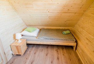 Gezellige slaapkamer in Ustecka Osada 45m2 in Denemarken met schuine houten muren en eenpersoonsbed.