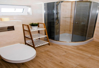 Modern bathroom at Ustecka Osada 45m2, Denmark, with glass shower, wooden floor, toilet, and shelf.