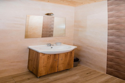 Badkamer met houten kastje, wastafel en spiegel in de Ustecka Osada 45m2 lodge in Denemarken.