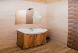 Badkamer met houten kastje, wastafel en spiegel in de Ustecka Osada 45m2 lodge in Denemarken.