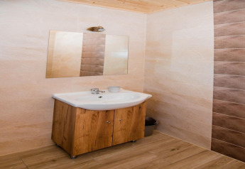 Bathroom with wooden cabinet, sink, mirror, and tiled walls at Ustecka Osada 45m2 lodge in Denmark.