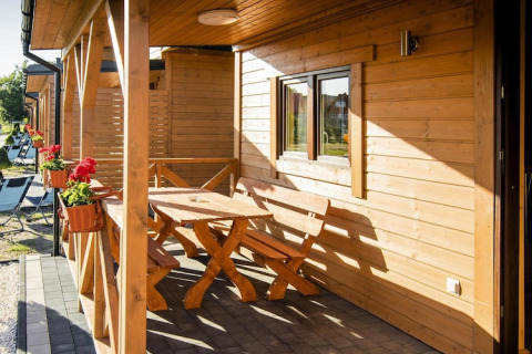 Zonnig terras aan Ustecka Osada 45m2 in Denemarken met houten zitjes, tafel en bloembakken.