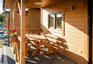 Zonnig terras aan Ustecka Osada 45m2 in Denemarken met houten zitjes, tafel en bloembakken.