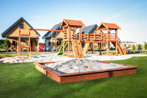 Speelplein met schommels, glijbaan en zandbak bij houten lodges van Ustecka Osada 45m2 in Denemarken.