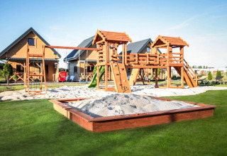 Speelplein met schommels, glijbaan en zandbak bij houten lodges van Ustecka Osada 45m2 in Denemarken.
