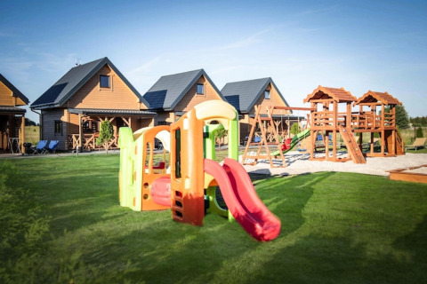 Speelplaats en houten lodges bij Ustecka Osada 45m2 in Denemarken, met glijbanen en groene grasvelden.