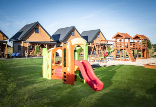 Speelplaats en houten lodges bij Ustecka Osada 45m2 in Denemarken, met glijbanen en groene grasvelden.