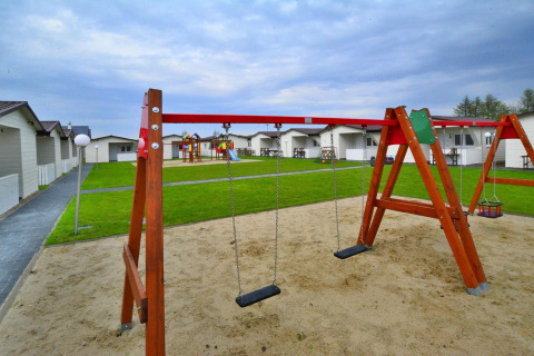 Legeplads med gynger og sandkasse foran moderne lodges hos Domki wakacyjne Przewłoka i Danmark.