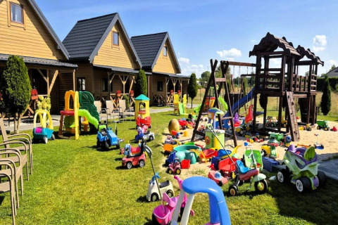 Speelzone bij Ustecka Osada 45m2 met speelgoedwagens, glijbanen en houten huisjes op groene gras.