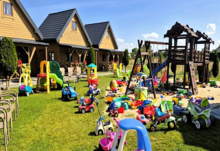 Speelzone bij Ustecka Osada 45m2 met speelgoedwagens, glijbanen en houten huisjes op groene gras.