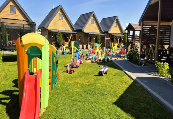 Outdoor playground with colorful toys and cabins in the background at Ustecka Osada 45m2 in Denmark.