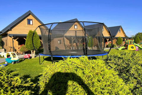 Trampoline en kinderspeelgoed in de tuin bij houten verblijven van Ustecka Osada 45m2 in Denemarken.