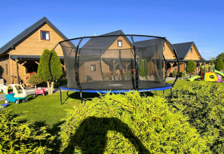 Trampoline en kinderspeelgoed in de tuin bij houten verblijven van Ustecka Osada 45m2 in Denemarken.