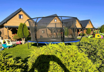 Trampoline and children’s toys in a garden outside wooden lodges at Ustecka Osada 45m2, Denmark.
