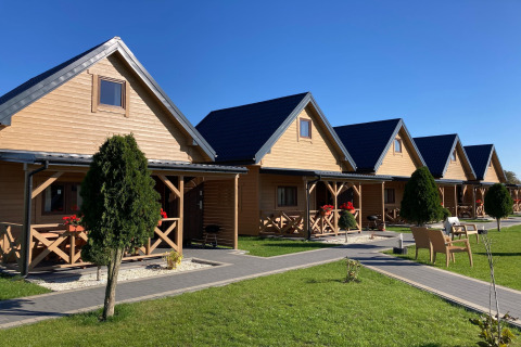 Rij charmante houten huisjes bij Ustecka Osada 45m2 in Denemarken, omringd door gras en blauwe lucht.