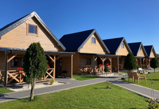 Rij charmante houten huisjes bij Ustecka Osada 45m2 in Denemarken, omringd door gras en blauwe lucht.