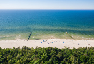 Luchtfoto van een rustige zandstrand met weinig mensen, blauwe zee en bos bij 'Ustecka Osada 45m2'.