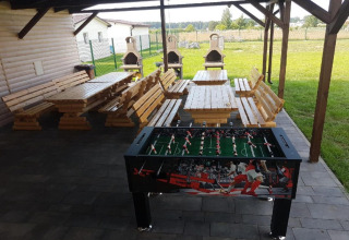Udendørs overdækket område ved Domki wakacyjne Przewłoka med borde, bænke, bordfodbold og grill.