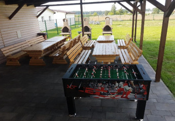 Zona esterna coperta a Domki wakacyjne Przewłoka con tavoli in legno, panche, calcio balilla e barbecue.