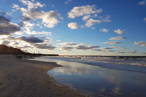 Strandbillede taget nær Domki wakacyjne Przewłoka med folk, havbølger og himmel i Danmark.