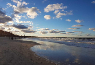 Strandbillede taget nær Domki wakacyjne Przewłoka med folk, havbølger og himmel i Danmark.