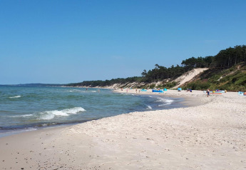 Plage de sable paisible avec vagues douces et dunes boisées près de Domki wakacyjne Przewłoka au Danemark.