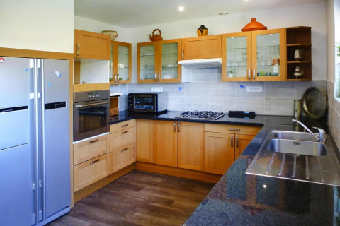 Moderne keuken in vakantiehuis Le Porge, Frankrijk, met houten kasten, oven, gaskookplaat en dubbele spoelbak.