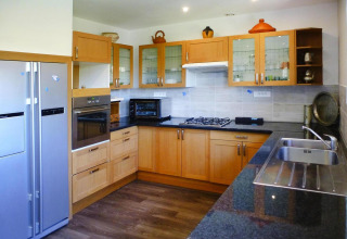Cucina moderna a Le Porge, Francia, con mobili in legno, forno, piano cottura a gas e doppio lavello.
