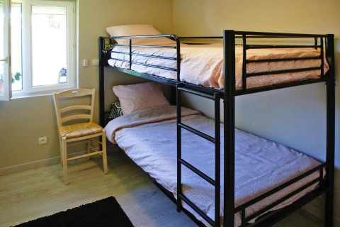 Habitación con litera, silla y ventana en Holiday home «Le Porge» en Francia, amueblada de manera sencilla.