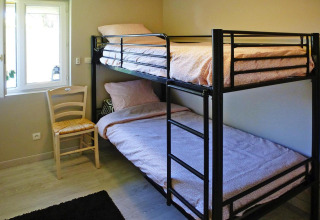 Camera con letto a castello, sedia e finestra al Holiday home «Le Porge» in Francia, arredamento semplice.