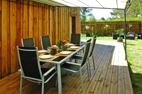 Buiten eetgedeelte op houten terras van Holiday home «Le Porge» in Frankrijk, bedekt met een zeil.