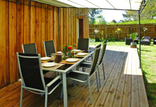 Coin repas extérieur sur terrasse en bois au Holiday home «Le Porge» en France, ombragé par une toile.