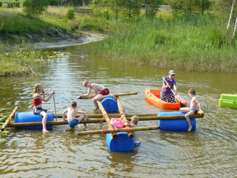 Kinderen spelen op een vlot en kano op het water bij Minicamping Falkenborg in Gelderland, Nederland.