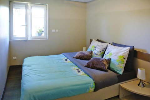 Knusse slaapkamer met tweepersoonsbed, blauw beddengoed en raam in Holiday home «Le Porge» in Frankrijk.