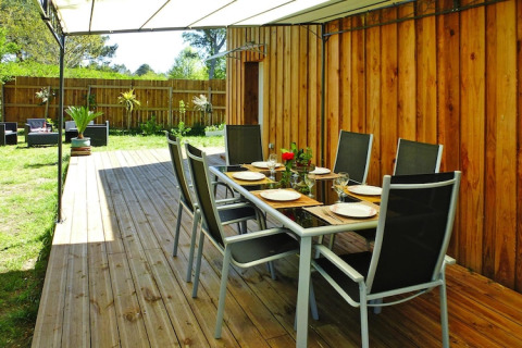 Udendørs spiseområde med bord og stole på træterrasse ved Holiday home «Le Porge» i Frankrig.