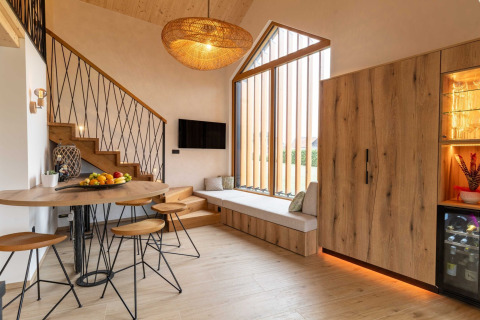 Modern lodge interior in Slovenia featuring warm wood accents, cozy seating, bar area, and large windows.