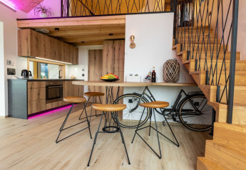 Interno lodge moderno con cucina in legno, sgabelli e bici riposta sotto la scala.